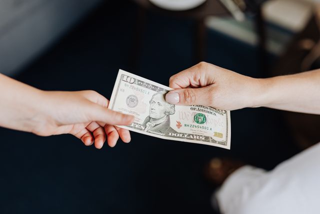 Two people exchanging a ten dollar bill